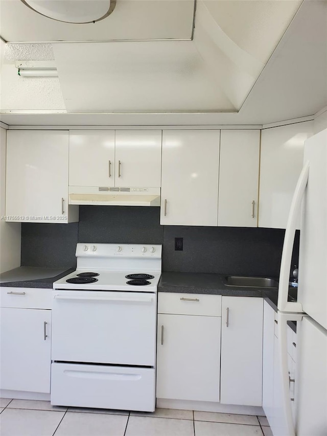 kitchen with dark countertops, white appliances, white cabinetry, and under cabinet range hood