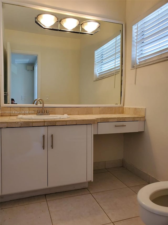 bathroom featuring baseboards, toilet, vanity, and tile patterned floors