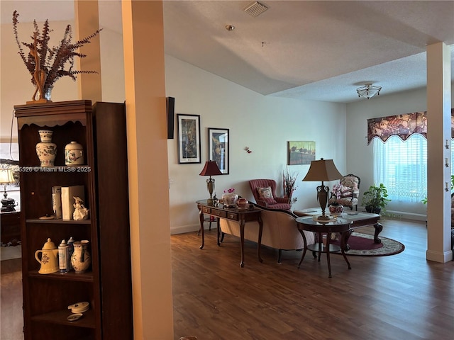 interior space featuring visible vents, baseboards, wood finished floors, and vaulted ceiling