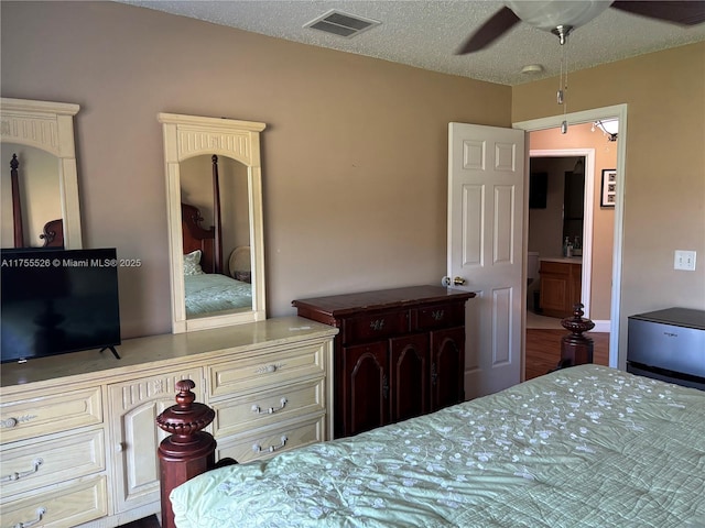 bedroom featuring a ceiling fan, visible vents, and a textured ceiling