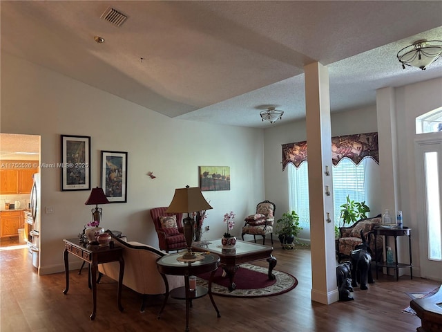 sitting room with visible vents, baseboards, a textured ceiling, and wood finished floors