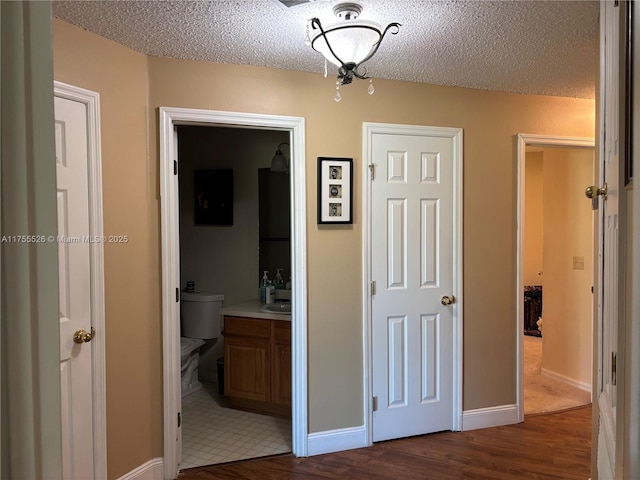 hallway featuring baseboards, a textured ceiling, and dark wood-style floors