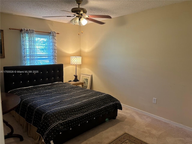 carpeted bedroom with a textured ceiling, baseboards, and a ceiling fan