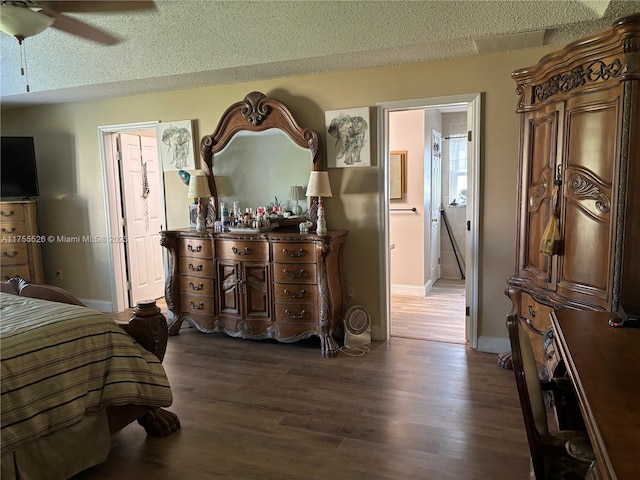 bedroom with ceiling fan, a textured ceiling, dark wood-type flooring, and baseboards