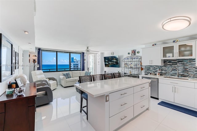 kitchen featuring light tile patterned flooring, a sink, backsplash, and stainless steel dishwasher