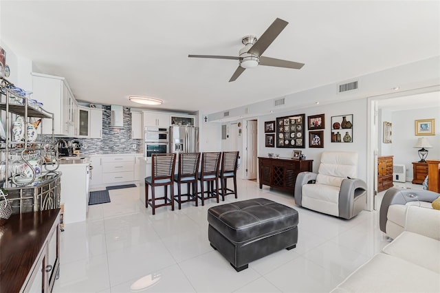 living room with light tile patterned floors, visible vents, and a ceiling fan