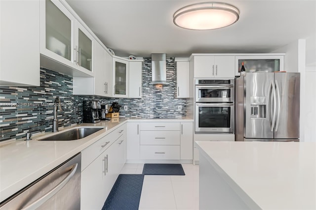 kitchen with stainless steel appliances, tasteful backsplash, light tile patterned flooring, a sink, and wall chimney range hood