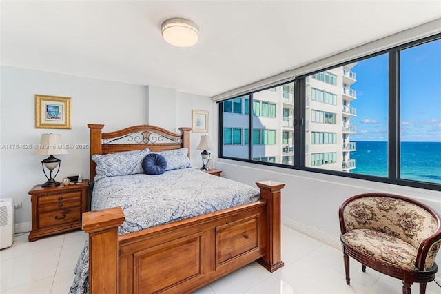 bedroom with a water view, baseboards, and light tile patterned floors