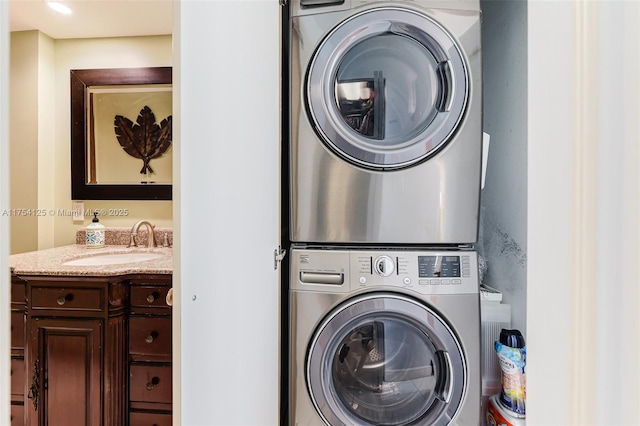 clothes washing area featuring stacked washing maching and dryer, laundry area, and a sink