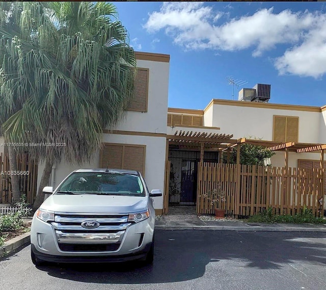 view of front of home featuring a pergola, fence, and stucco siding