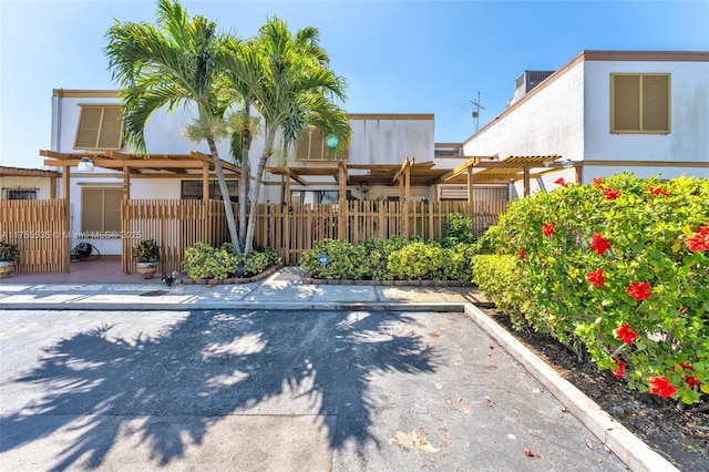 view of front of home featuring a pergola, fence, and stucco siding