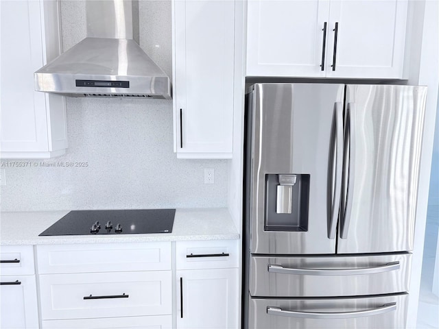 kitchen with white cabinets, stainless steel refrigerator with ice dispenser, wall chimney exhaust hood, and black electric cooktop