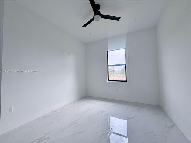 empty room with ceiling fan, marble finish floor, and baseboards