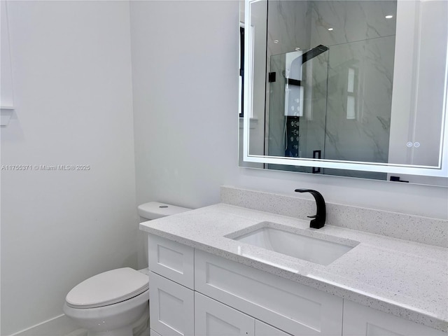 bathroom featuring a marble finish shower, vanity, and toilet