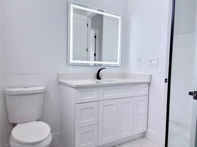 bathroom featuring toilet, marble finish floor, baseboards, and vanity