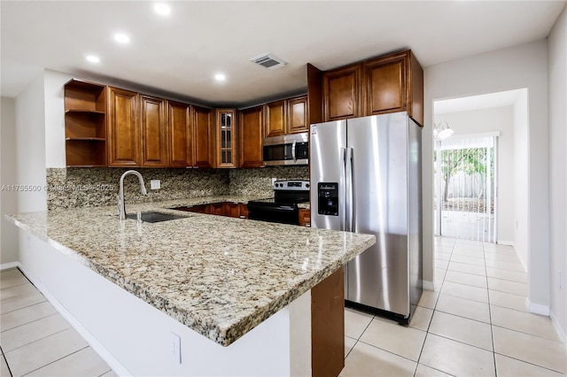 kitchen featuring light stone counters, open shelves, appliances with stainless steel finishes, a sink, and a peninsula