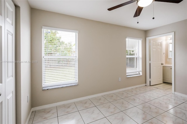 unfurnished bedroom with multiple windows, ceiling fan, baseboards, and light tile patterned flooring