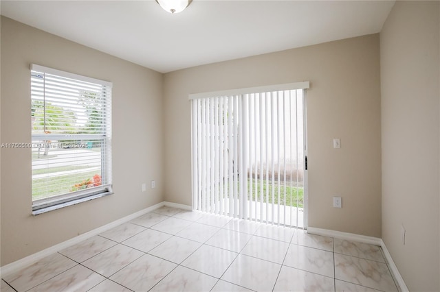 unfurnished room with light tile patterned flooring and baseboards