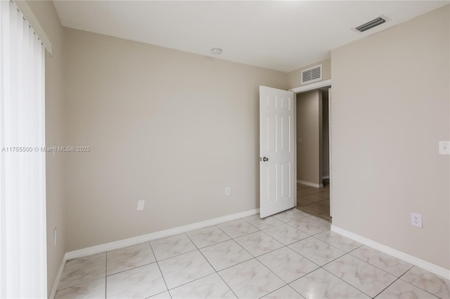 empty room featuring visible vents, baseboards, and light tile patterned flooring