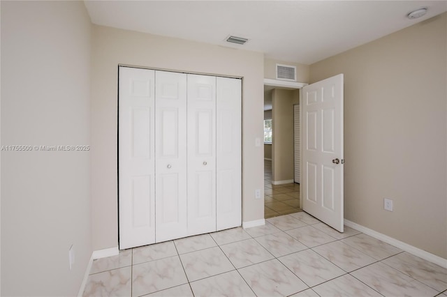 unfurnished bedroom featuring light tile patterned floors, baseboards, visible vents, and a closet