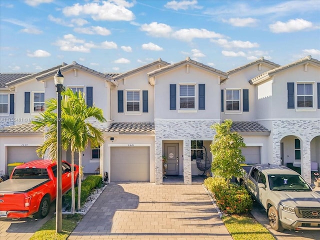 view of front of home featuring a garage, decorative driveway, a tile roof, and stucco siding