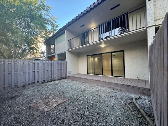 back of house with a balcony, fence, and stucco siding