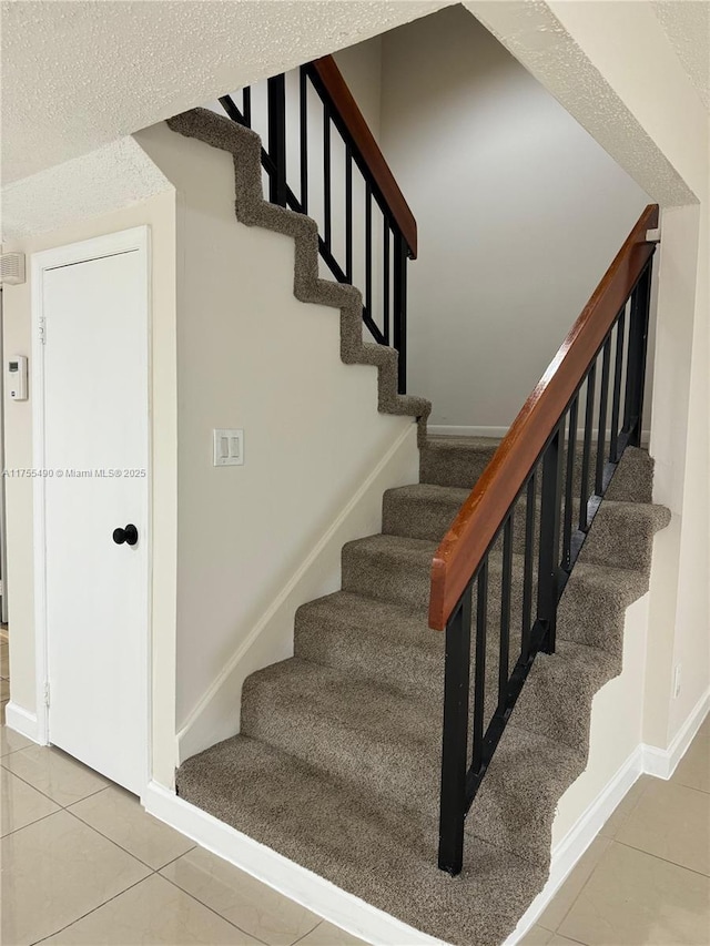 stairway with baseboards and tile patterned floors