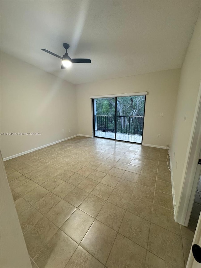 tiled empty room with ceiling fan and baseboards