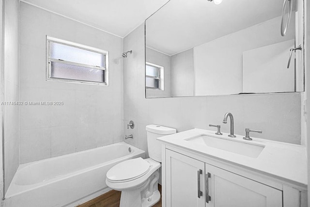 bathroom featuring toilet, wood finished floors, vanity, tile walls, and shower / washtub combination