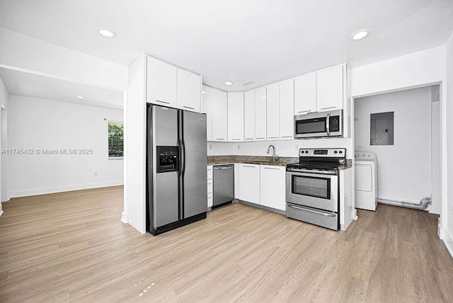 kitchen with light wood-type flooring, appliances with stainless steel finishes, washer / clothes dryer, and a sink