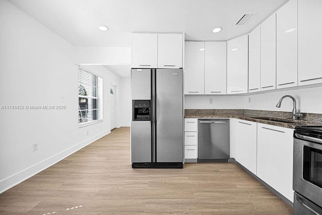 kitchen featuring stainless steel appliances, a sink, visible vents, white cabinetry, and light wood finished floors