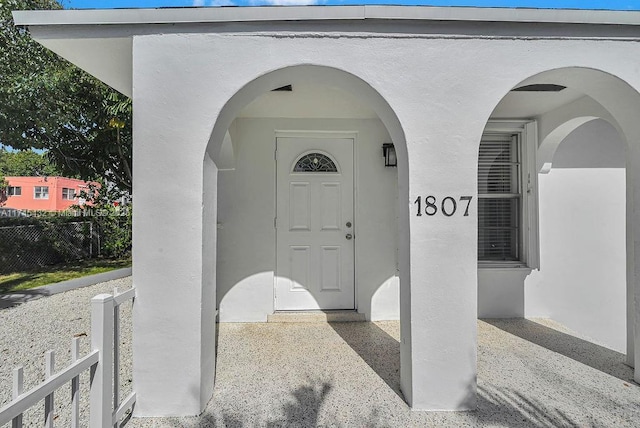 view of exterior entry featuring fence and stucco siding