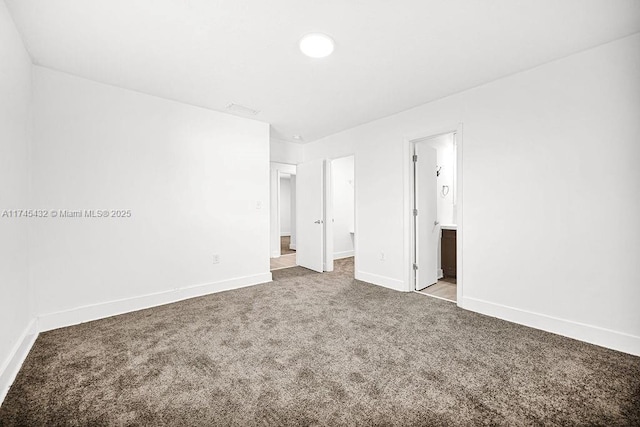 unfurnished bedroom featuring baseboards, visible vents, connected bathroom, carpet, and a spacious closet