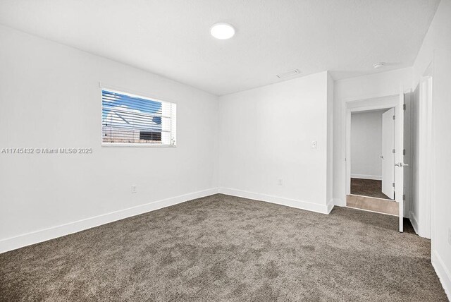 carpeted empty room featuring visible vents and baseboards