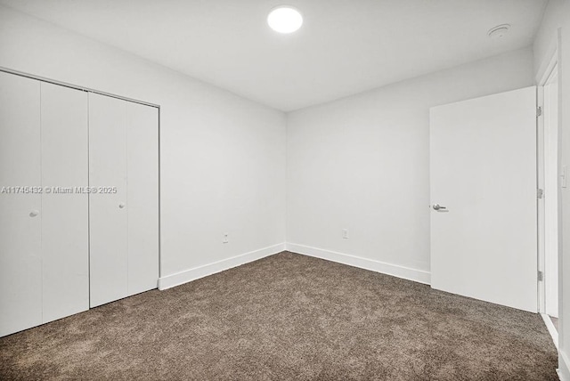 unfurnished bedroom featuring a closet and dark carpet