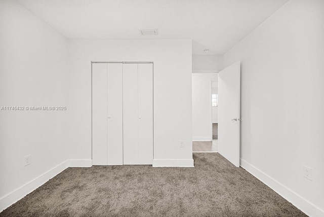 unfurnished bedroom with carpet floors, a closet, visible vents, and baseboards