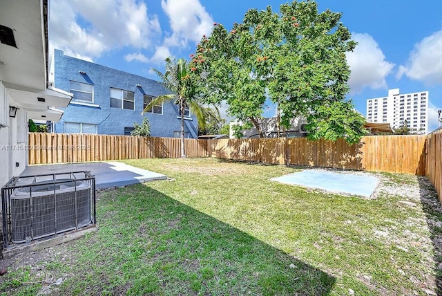 view of yard with a fenced backyard, central AC unit, and a patio