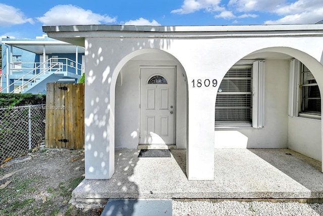 view of exterior entry featuring fence and stucco siding