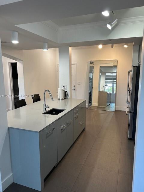 kitchen featuring ornamental molding, freestanding refrigerator, light countertops, and a sink