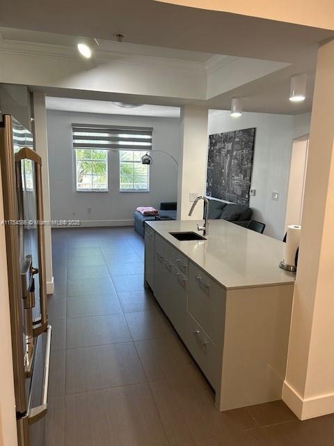 kitchen with ornamental molding, open floor plan, freestanding refrigerator, light countertops, and a sink