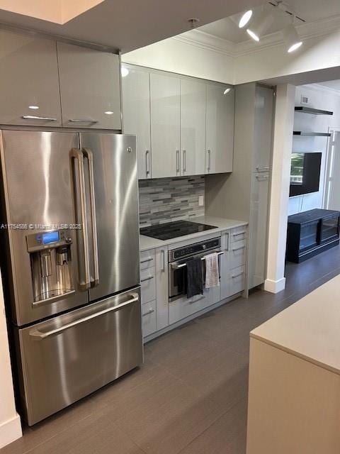 kitchen with decorative backsplash, modern cabinets, appliances with stainless steel finishes, ornamental molding, and light countertops