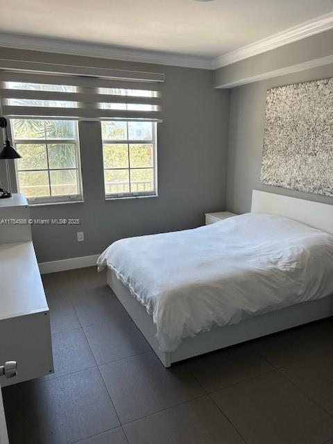 bedroom with dark tile patterned flooring, crown molding, and baseboards