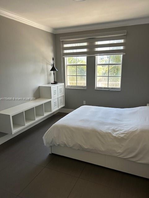 unfurnished bedroom with ornamental molding and dark tile patterned flooring