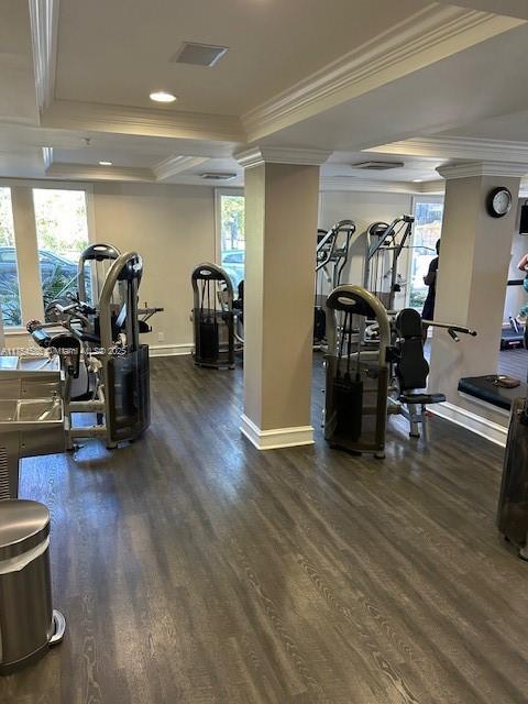 gym featuring dark wood-type flooring, a healthy amount of sunlight, and crown molding