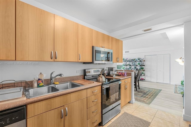 kitchen featuring light tile patterned flooring, a sink, visible vents, light countertops, and appliances with stainless steel finishes