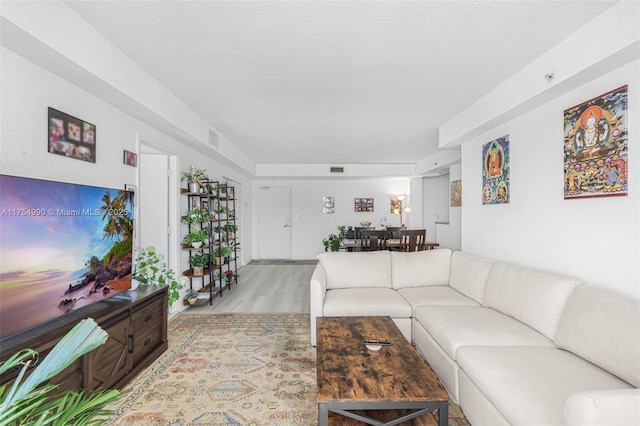 living area with visible vents, a textured ceiling, and wood finished floors