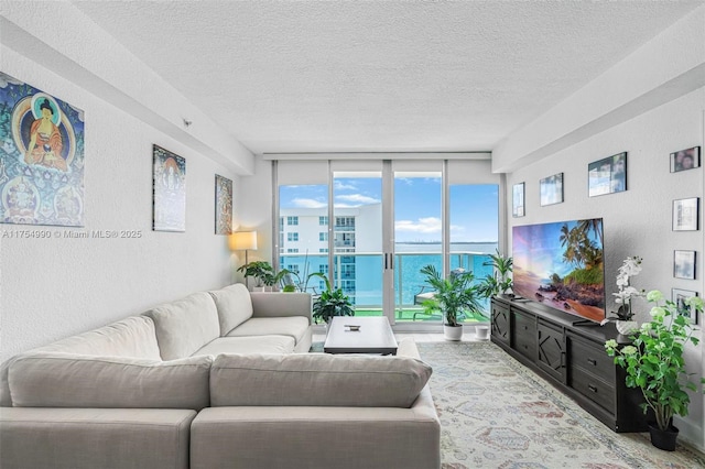 living area featuring floor to ceiling windows, a textured wall, and a textured ceiling