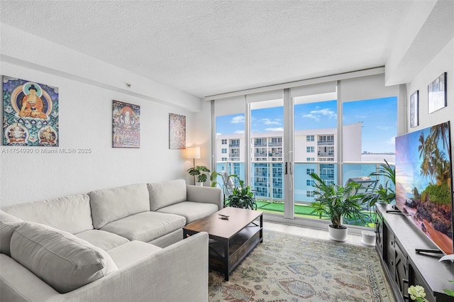 living room with a textured ceiling, a wall of windows, a wealth of natural light, and wood finished floors