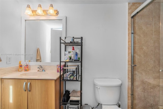 bathroom with toilet, a tile shower, and vanity