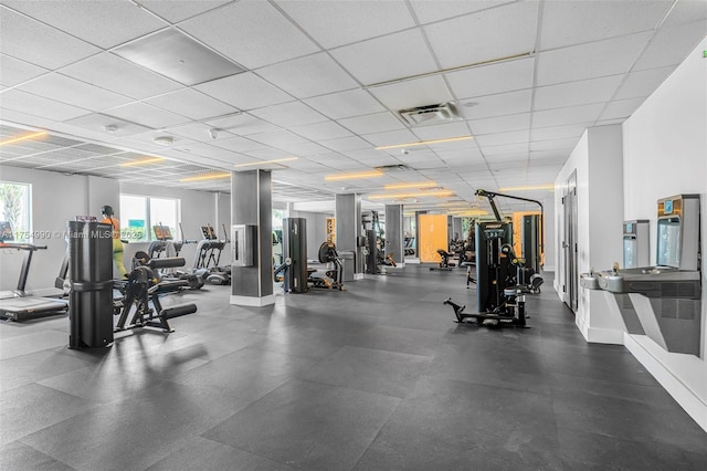 gym with a drop ceiling, visible vents, and baseboards